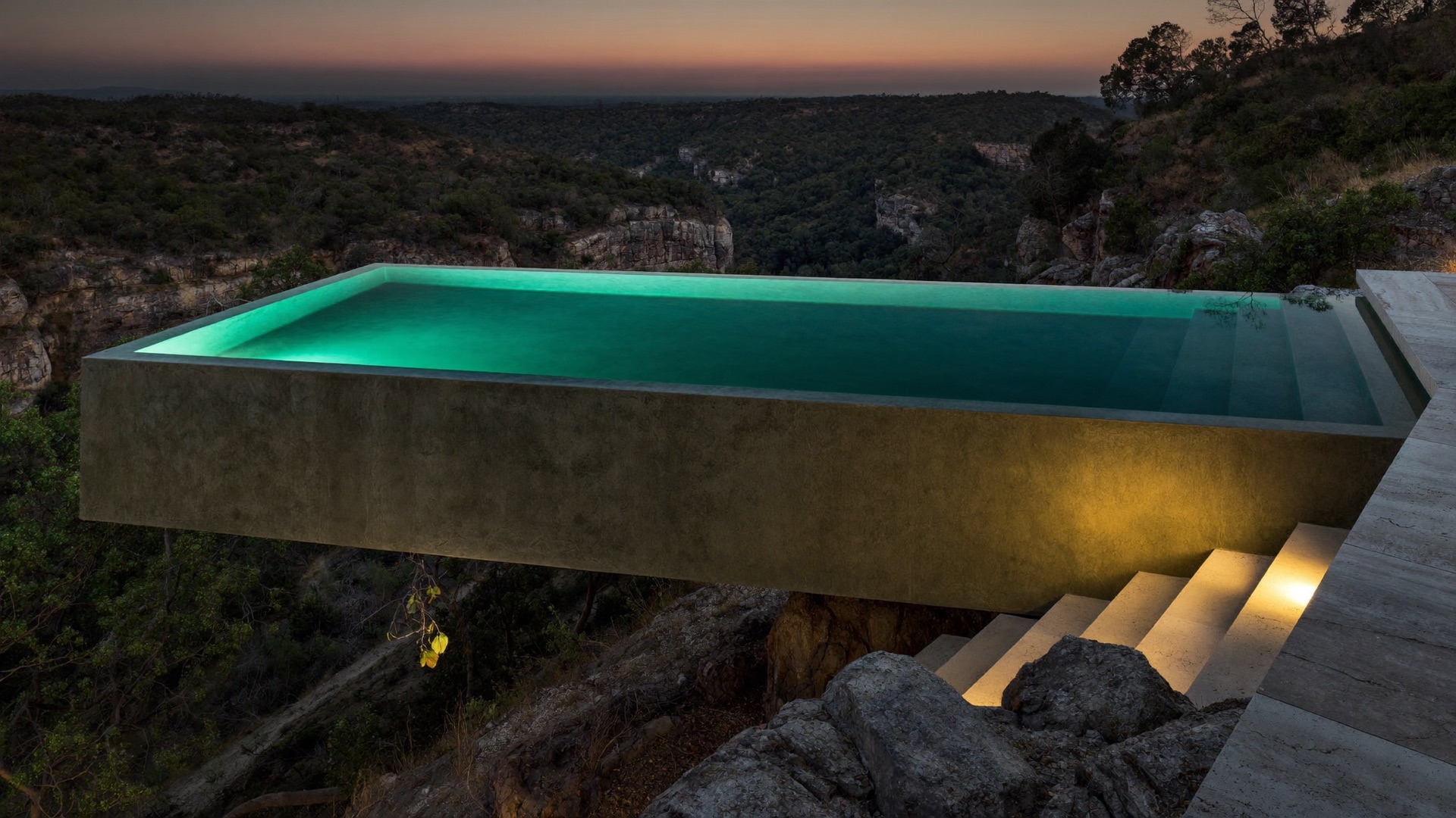 Cantilevered infinity-edge gunite pool glowing over a Barton Creek canyon at dusk
