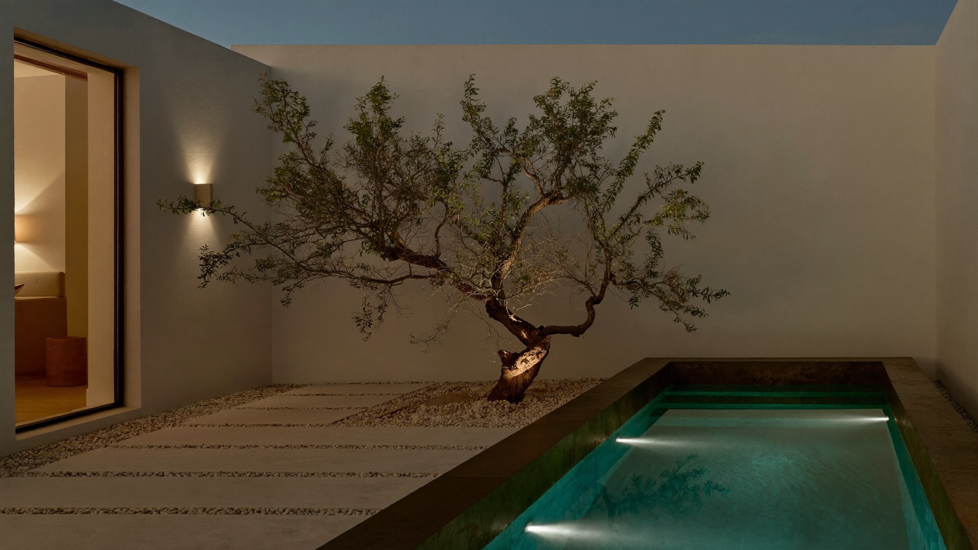 Courtyard plunge pool with white plaster walls and a single lit oak in Westlake